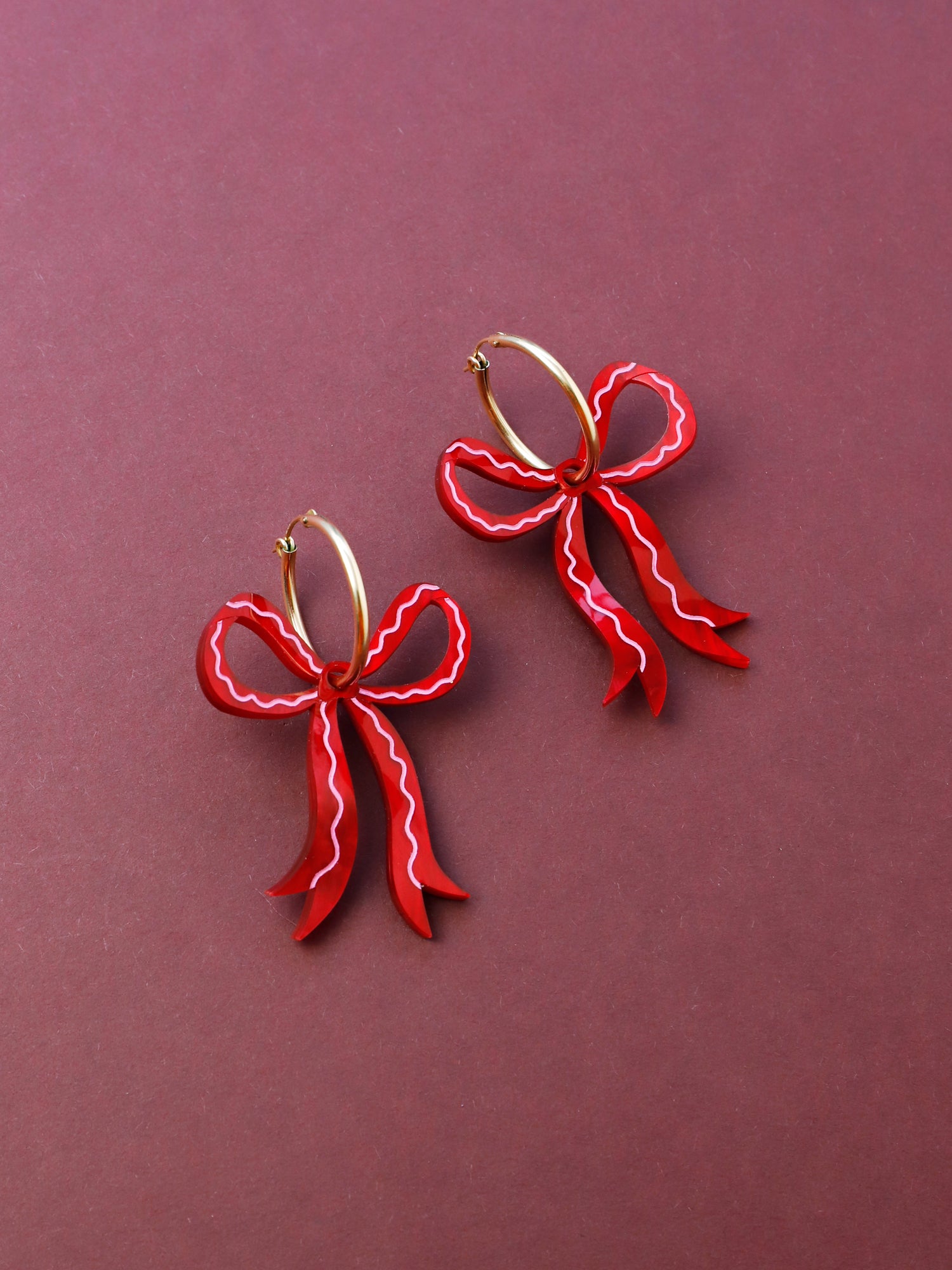 Bow hoop earrings made from red marbled acrylic with hand-inked details. Finished off with high quality glass pearls and 14k gold-filled findings. Each bow is hand-sculpted into a 3D form giving it a lovely realistic ribbon-like effect. Handmade in London by Wolf & Moon.