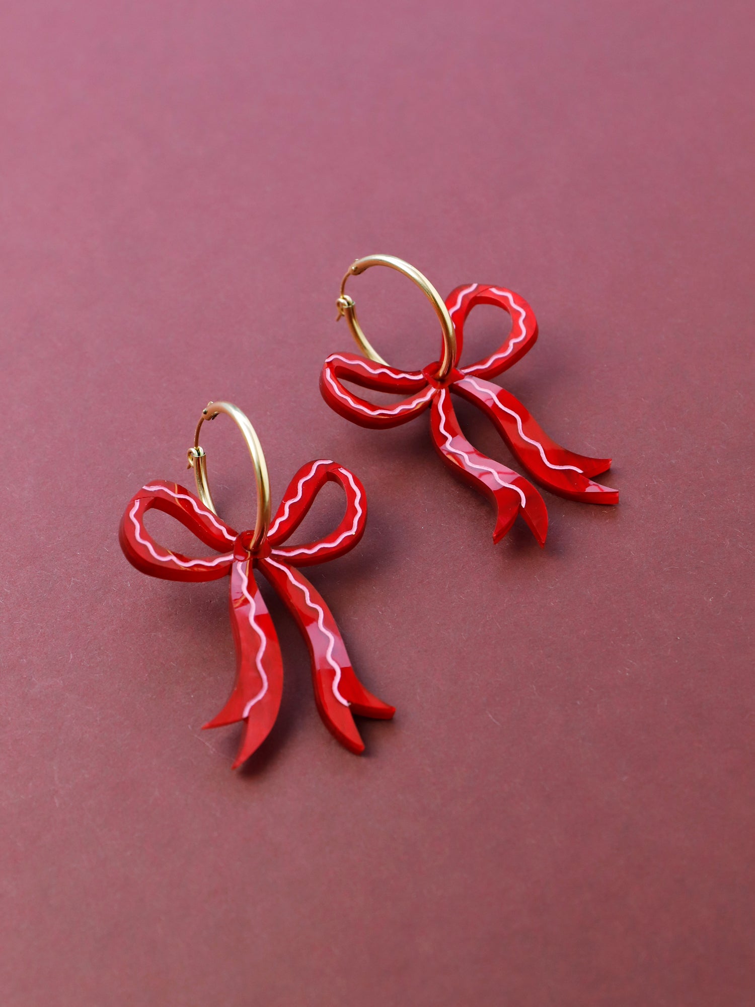 Bow hoop earrings made from red marbled acrylic with hand-inked details. Finished off with high quality glass pearls and 14k gold-filled findings. Each bow is hand-sculpted into a 3D form giving it a lovely realistic ribbon-like effect. Handmade in London by Wolf & Moon.