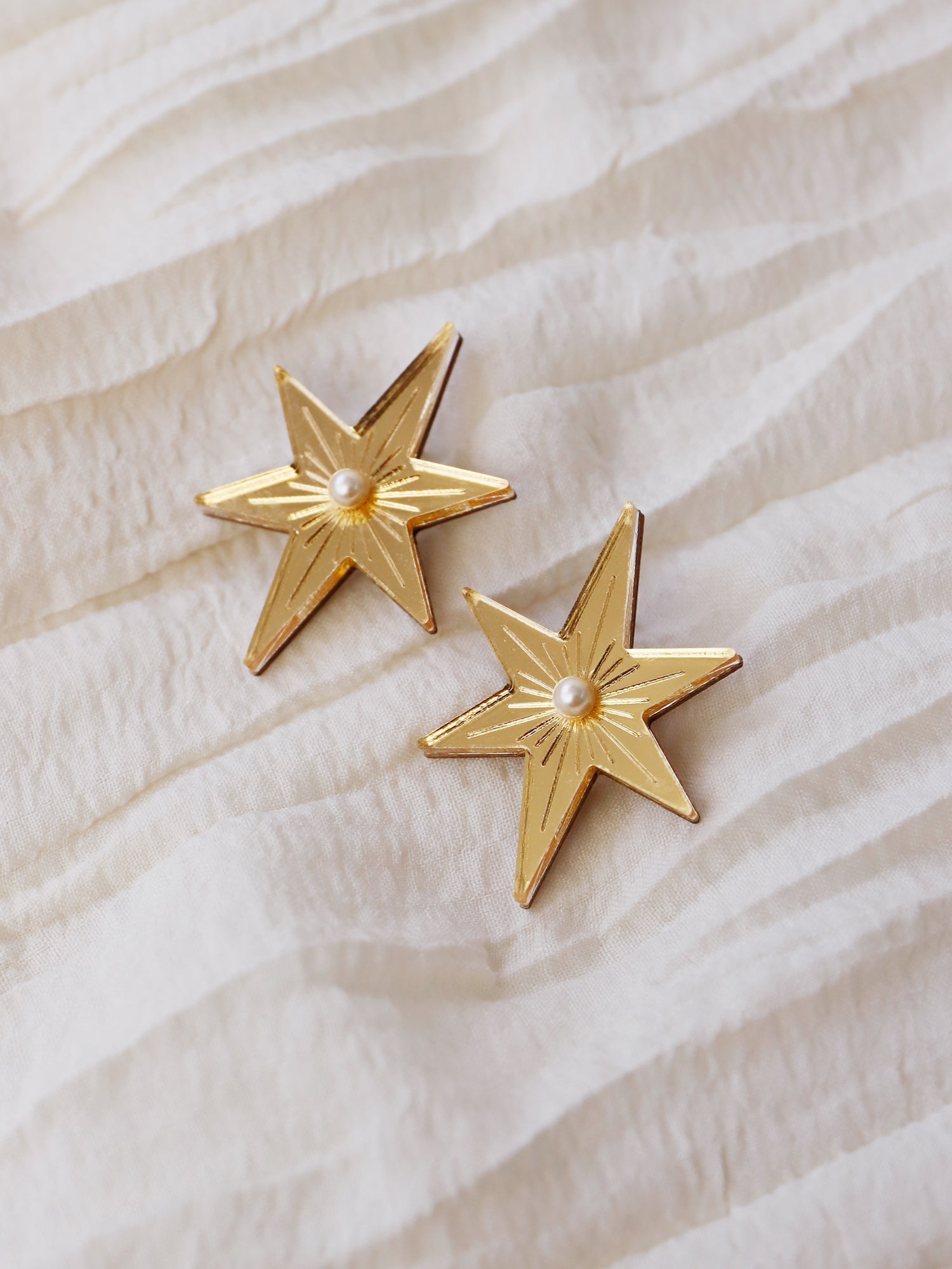 Statement star studs made with gold mirrored acrylic, embellished with glass pearls and hand inked details. Handmade in London by Wolf & Moon.