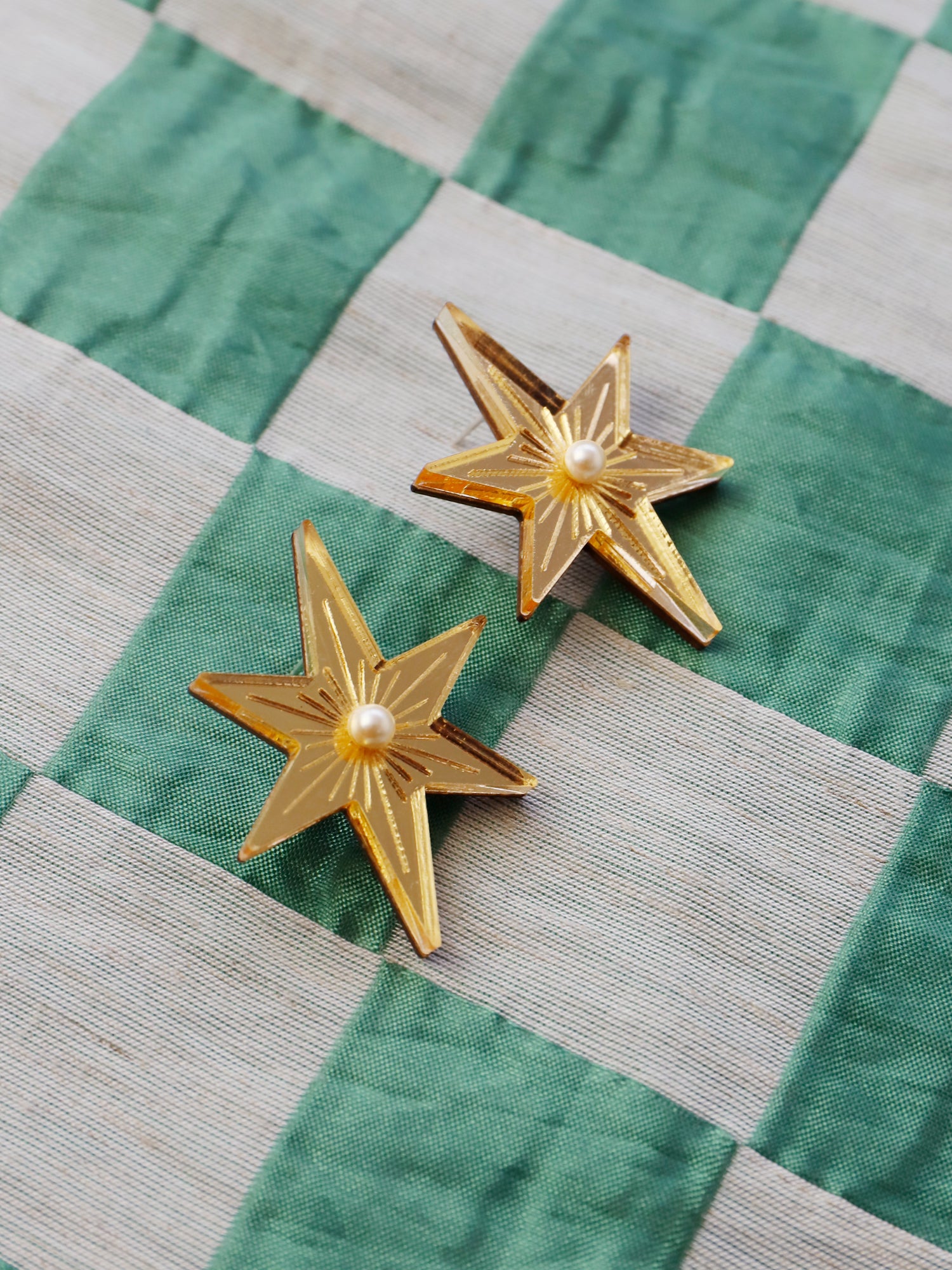 Statement star studs made with gold mirrored acrylic, embellished with glass pearls and hand inked details. Handmade in London by Wolf & Moon.